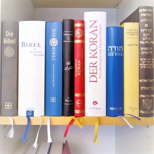 In einen Bücherregal stehen nebeneinander je drei verschiedene Ausgaben der Bibel, des Korans sowie zwei Ausgaben der Tora und eine Mischna